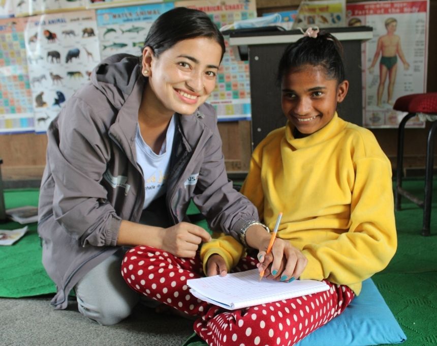 A woman helps a student with her schoolwork in a classroom in Nepal